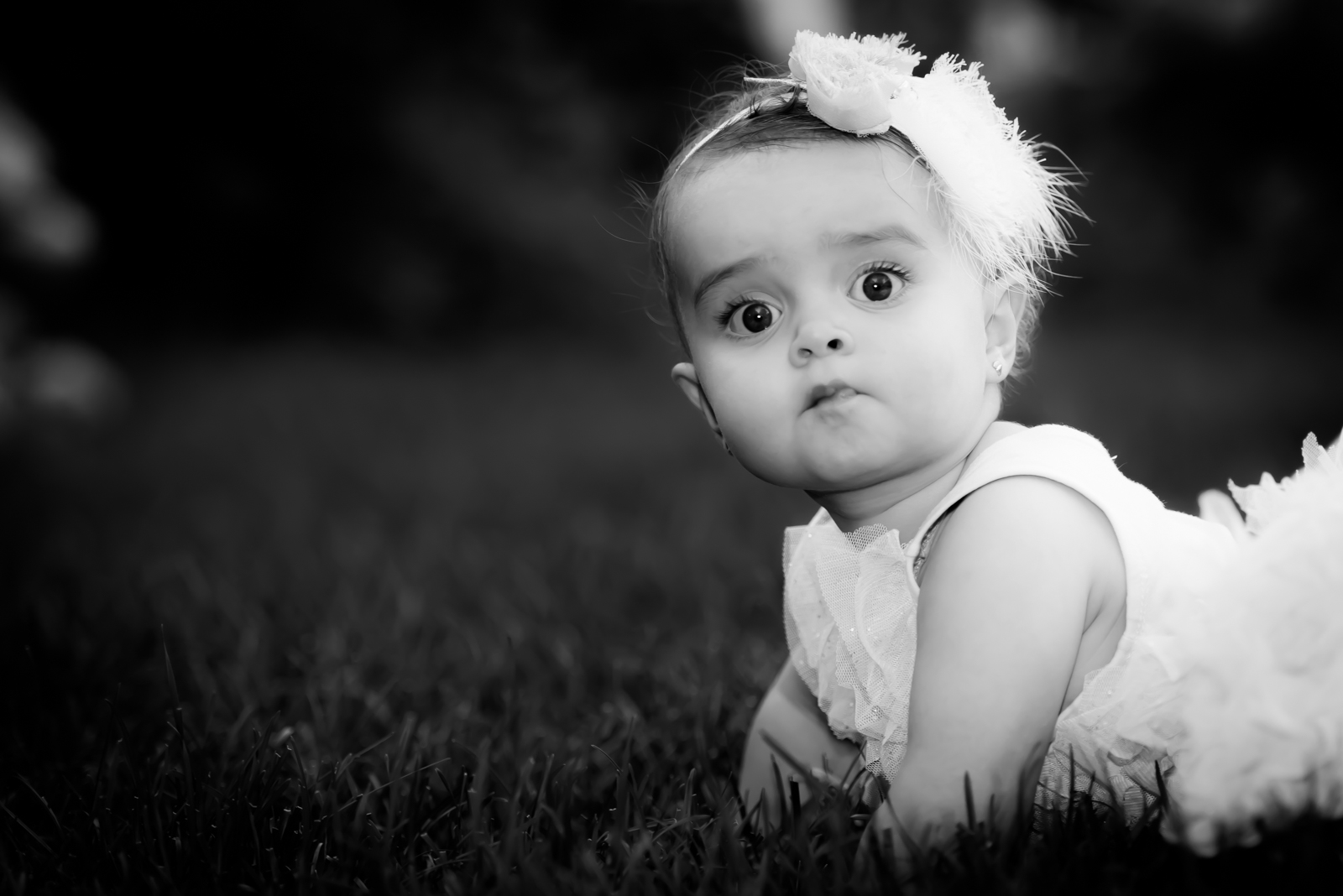 Baby with headband lying in grass